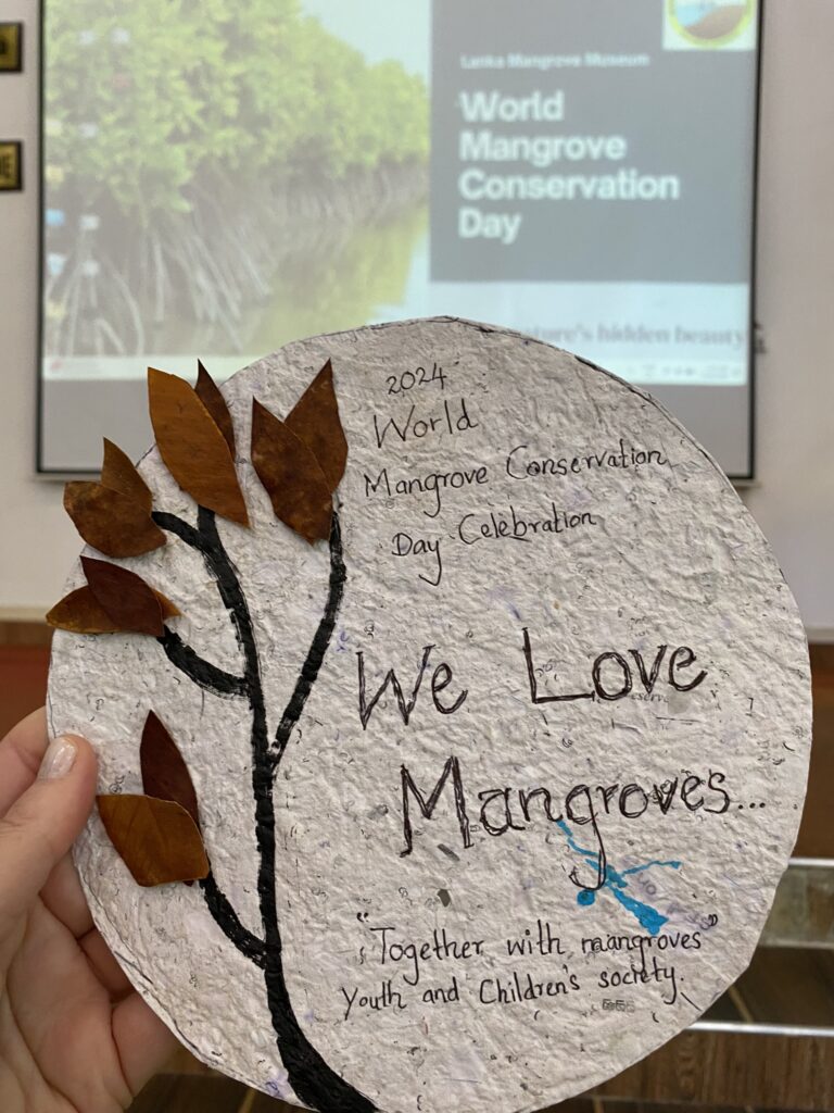 A handmade piece of paper with art of a tree that reads, "We love mangroves"