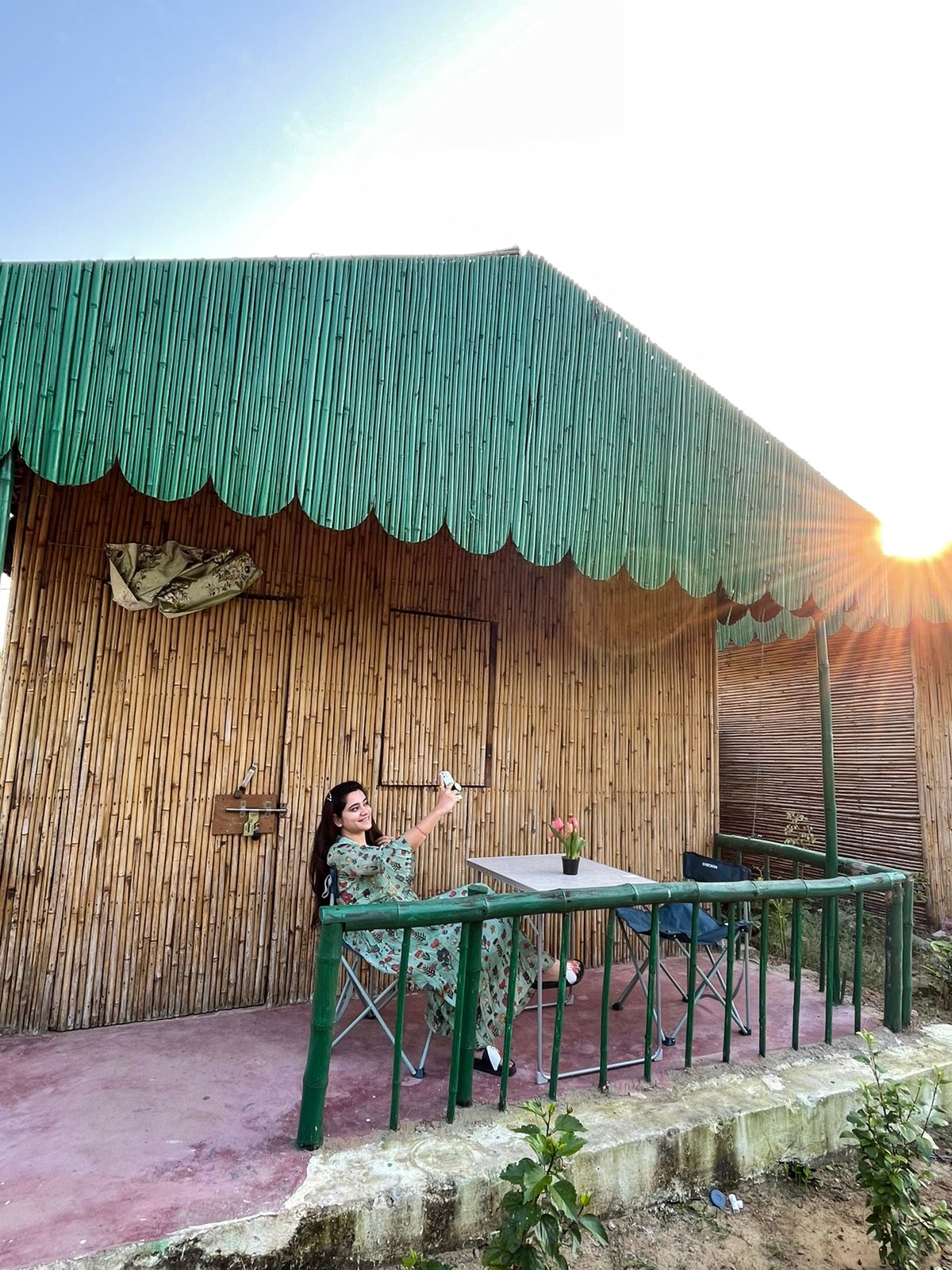 Woman takes a selfie outside cabin with sun at horizon in background