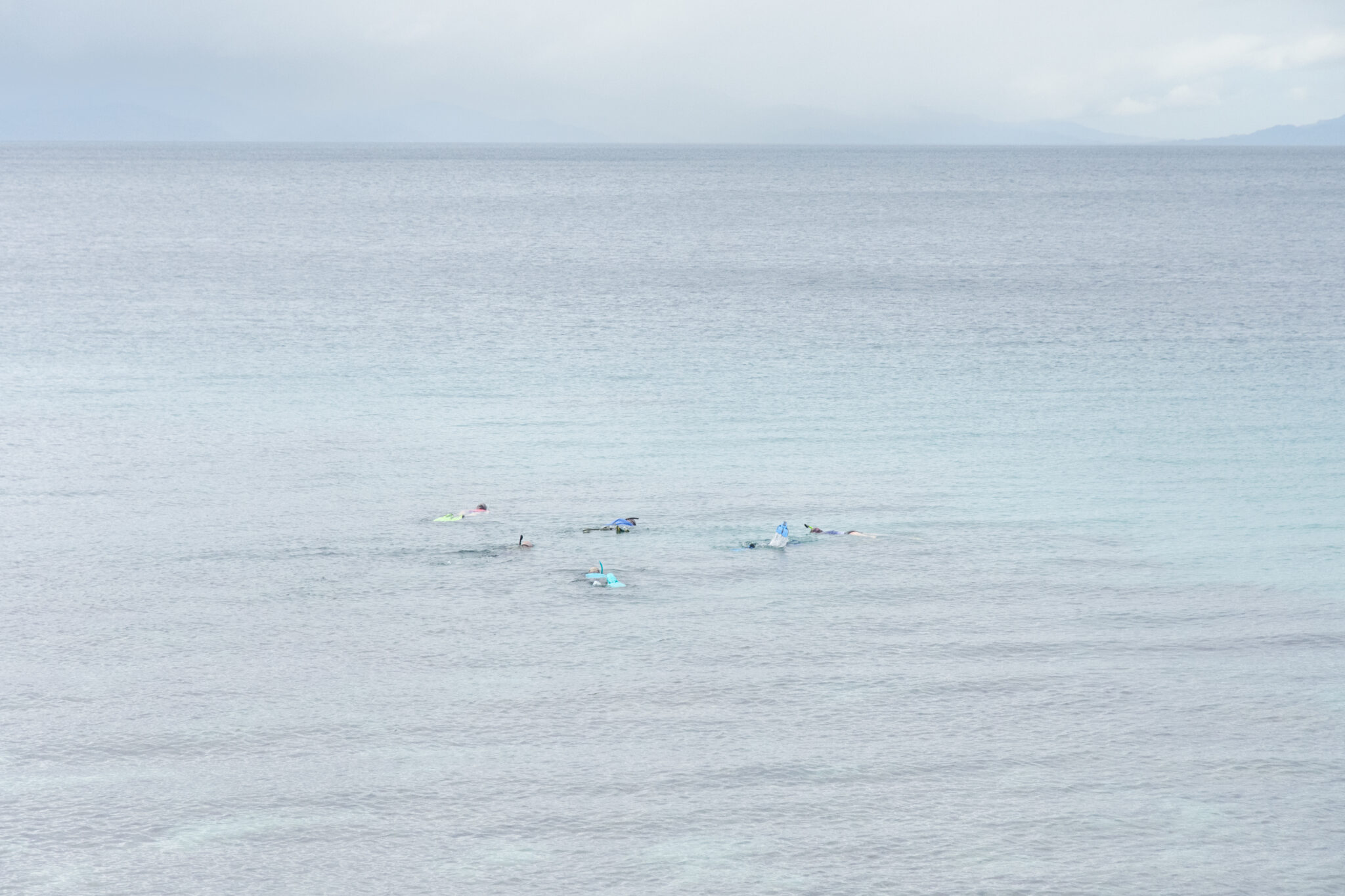 People snorkel in ocean, seen from above