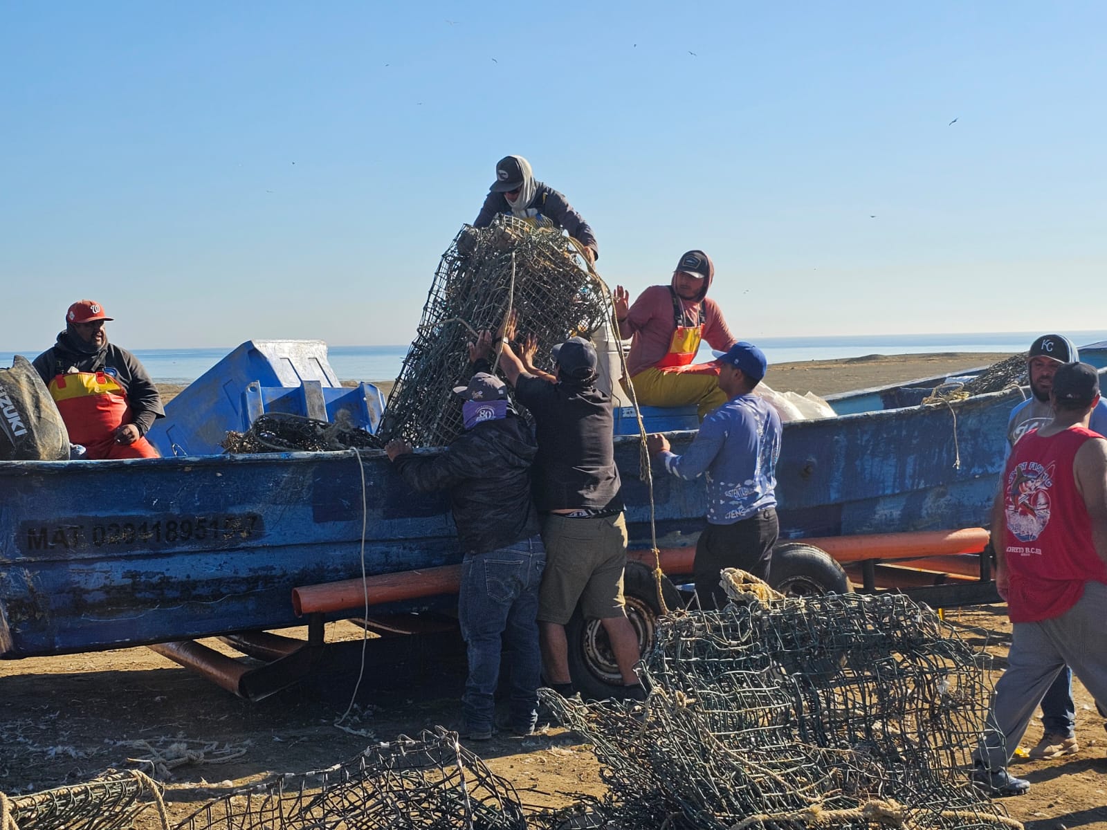 A group of people load a bunch of scrap metal into a boat