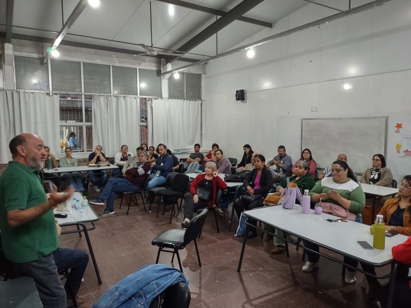 A man speaks in front of a room full of people sitting at tables