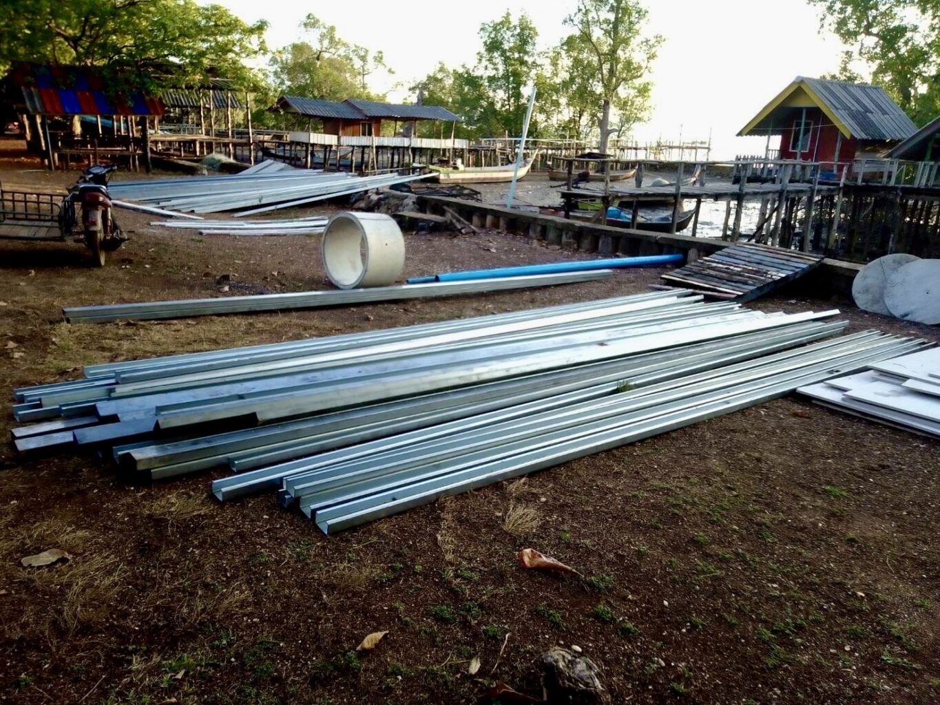 Long metal girders and other construction materials are laid out on the ground.