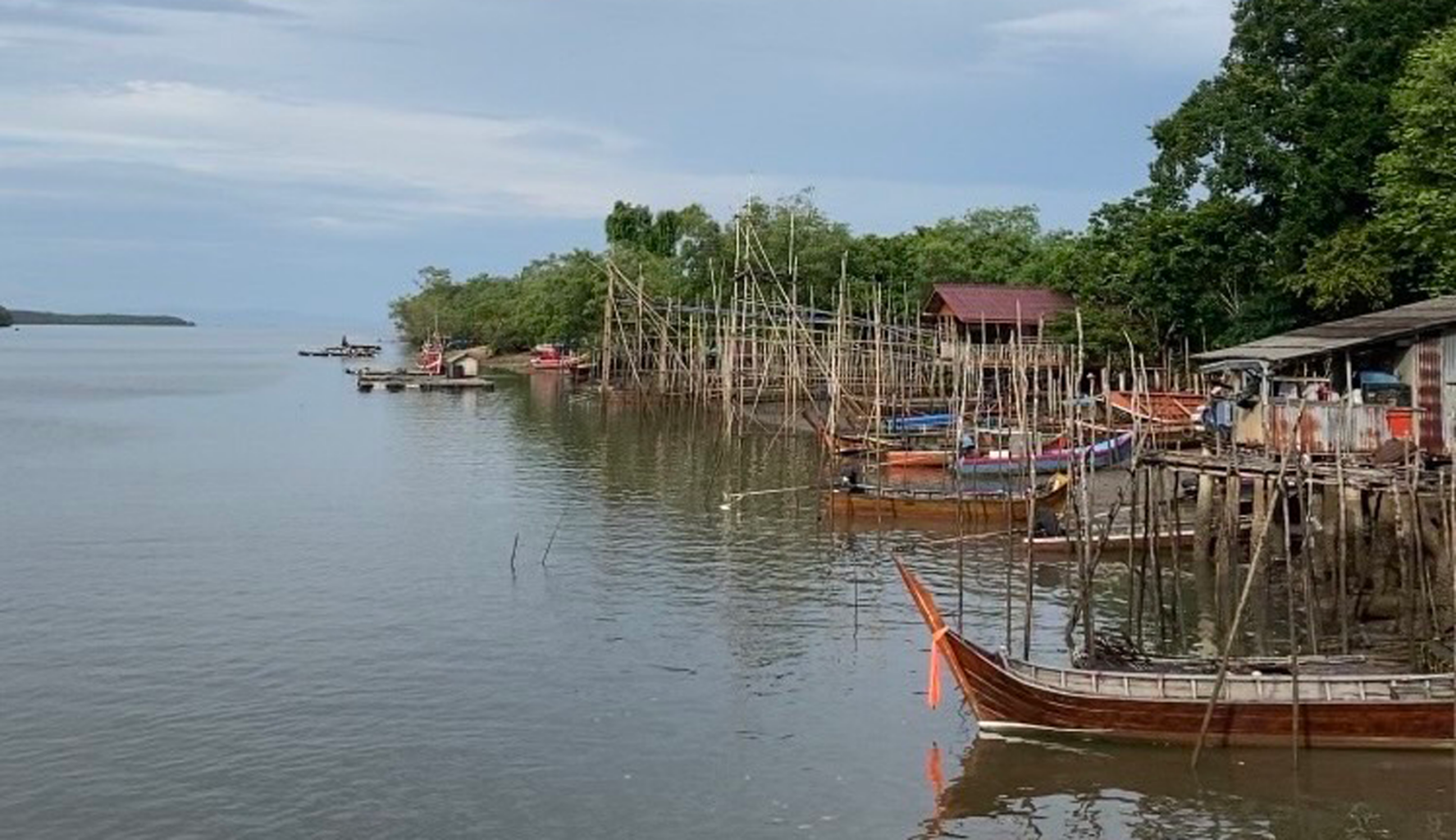 Docks, boats, structures, and bamboo scaffolding just out over water