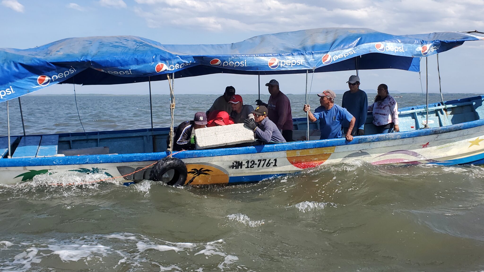 People on boat prepare to drop large cement structure into ocean.