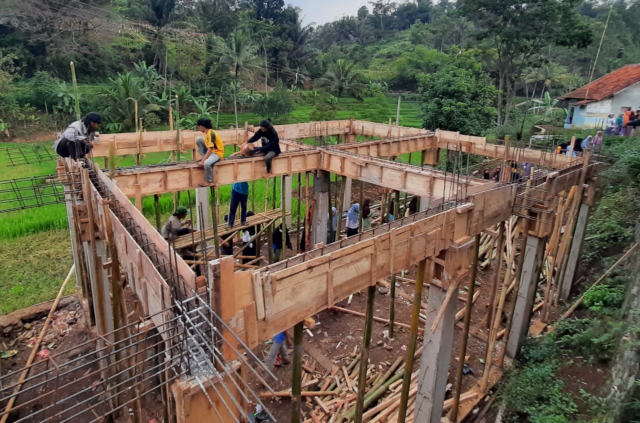 The frame of a building is assembled with forest in the background