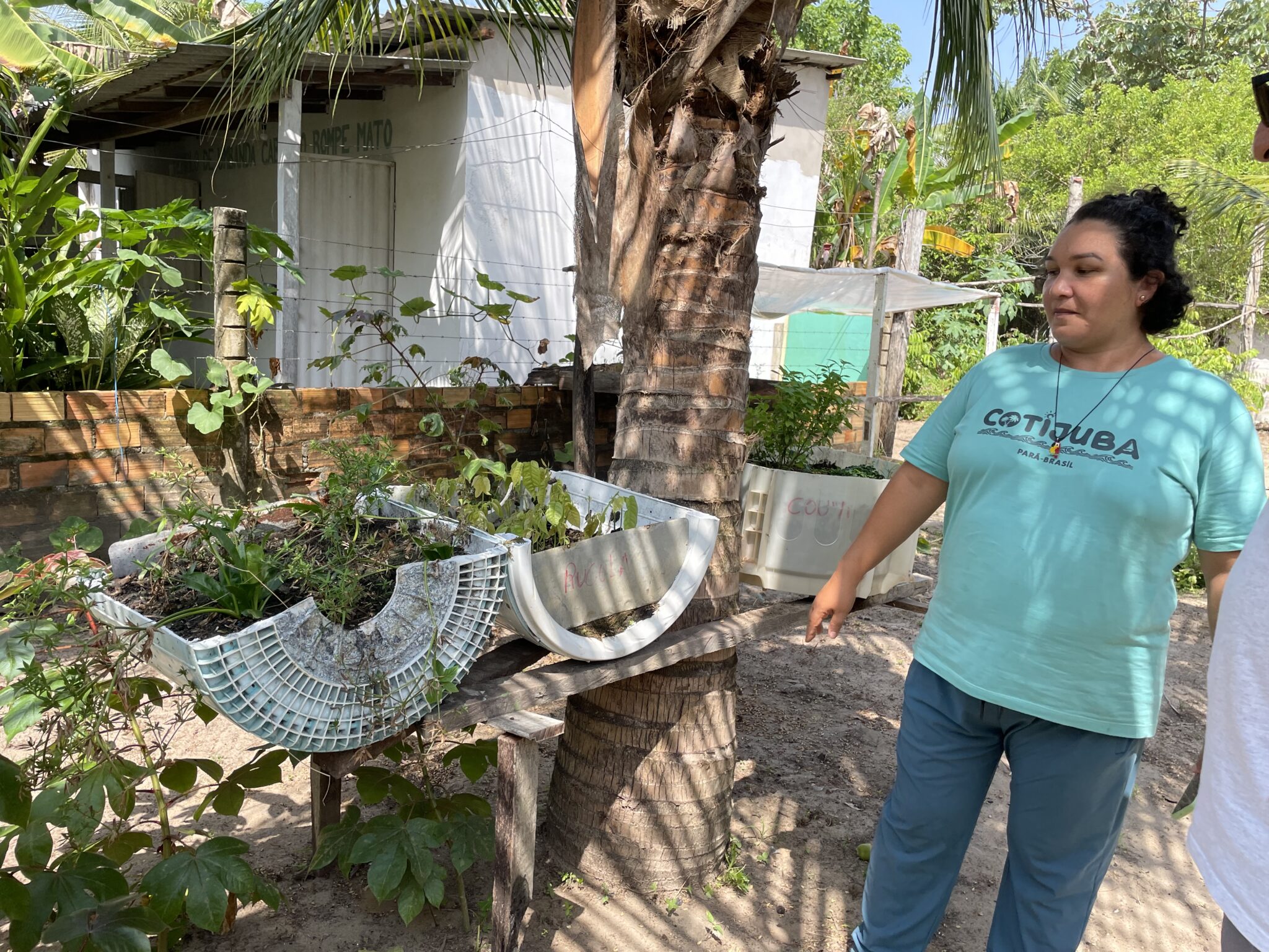 A woman in a blue shirt stands next to some planters