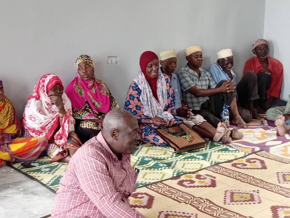 A group of people sit together on colorful rugs